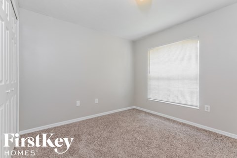a bedroom with carpet and a large window