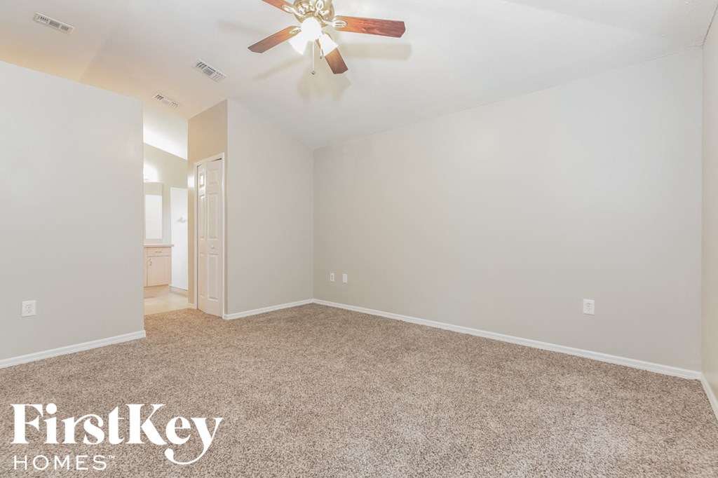 the spacious living room with carpeting and a ceiling fan