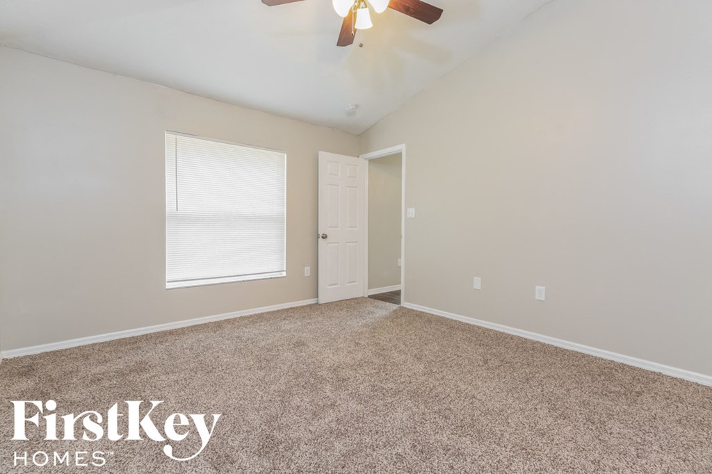 the spacious living room with carpeting and a ceiling fan
