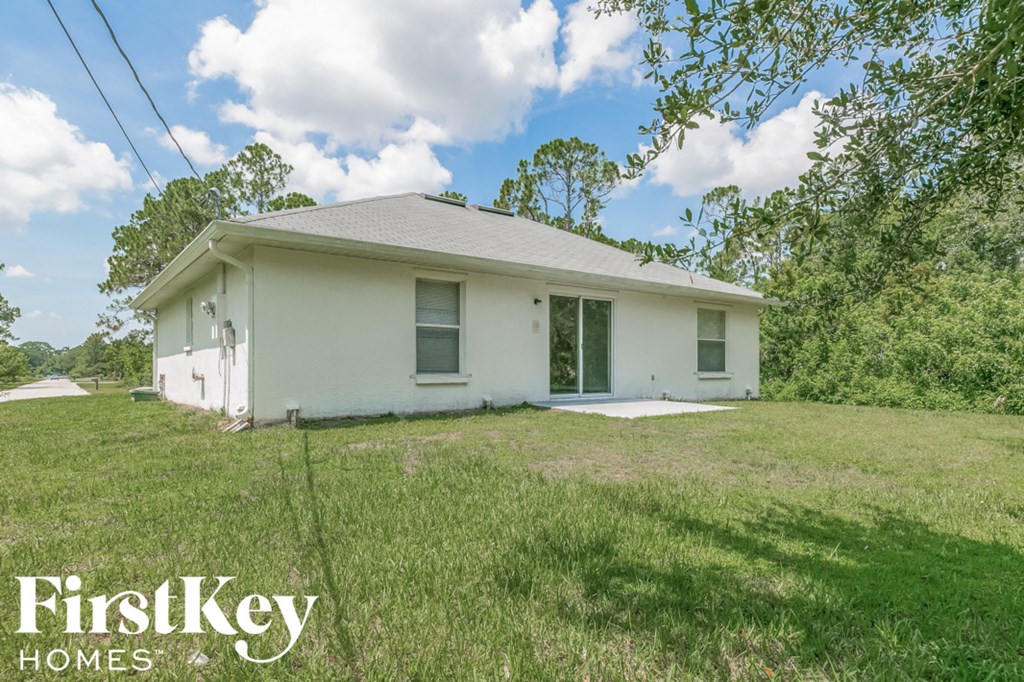 a small white house with a lawn and trees
