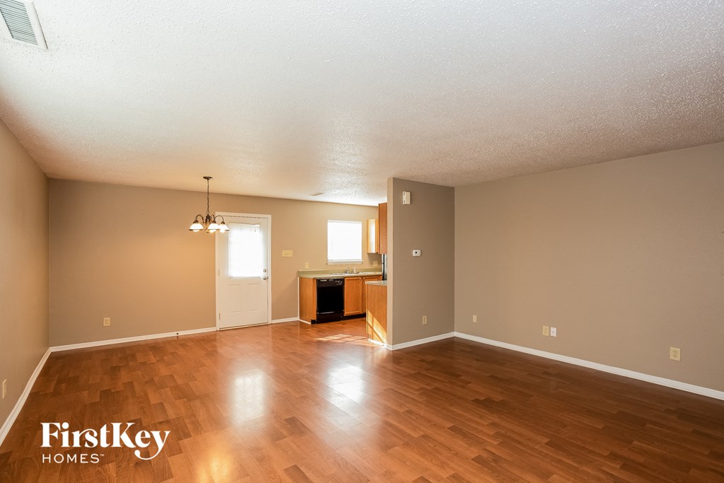 A spacious room with wooden floors and a ceiling fan.