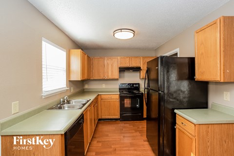 A kitchen with wooden cabinets and a black refrigerator.