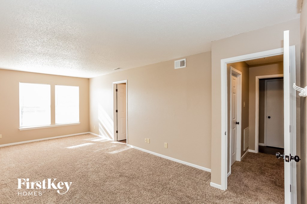 A room with a carpeted floor and a doorway leading to another room.
