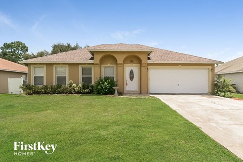 a beige house with a garage door and a lawn