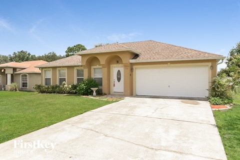a beige house with a white garage door and a lawn