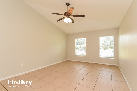 an empty living room with a ceiling fan and a tiled floor