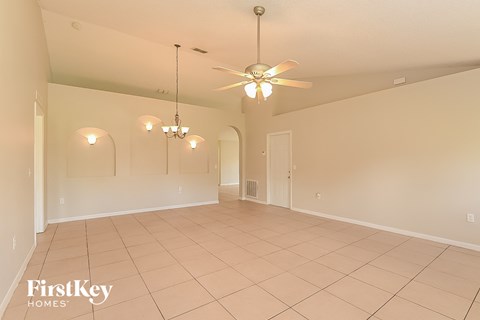 a spacious living room with a ceiling fan and a tiled floor