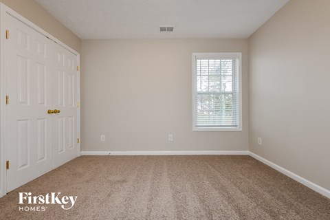 a bedroom with carpet and a white door and window