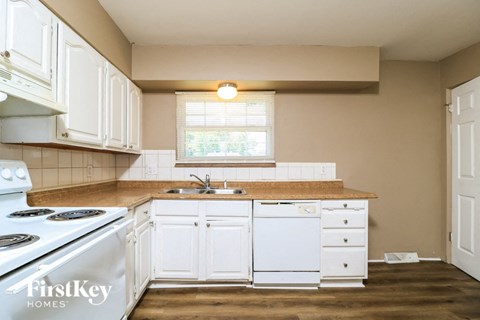 a kitchen with white cabinets and a stove and a sink