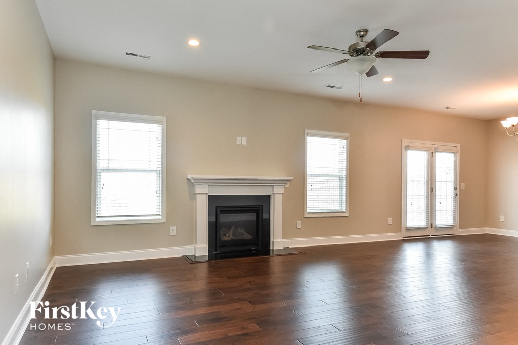 A spacious living room with a fireplace and a ceiling fan.