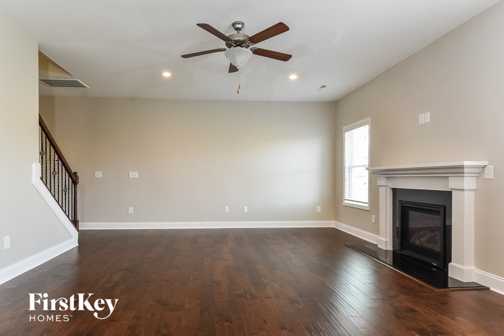 A spacious living room with a fireplace and a ceiling fan.