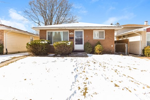 the front of a brick house in the snow