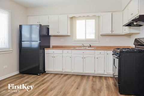 a kitchen with white cabinets and a black refrigerator