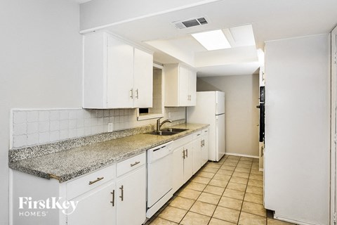 A kitchen with white cabinets and a granite countertop.