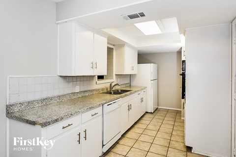 A kitchen with white cabinets and a granite countertop.