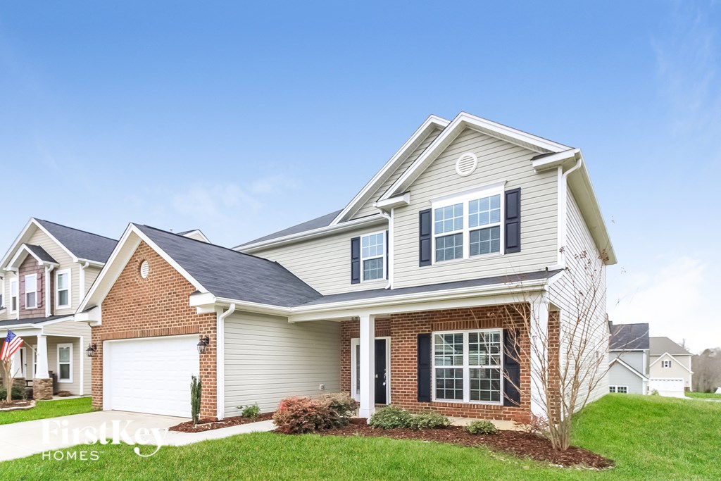 A two-story house with a garage and a brick chimney.
