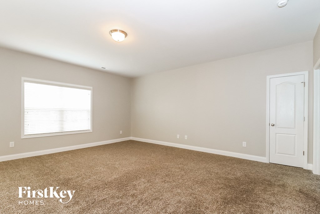 A room with a carpeted floor and a door on the right side.
