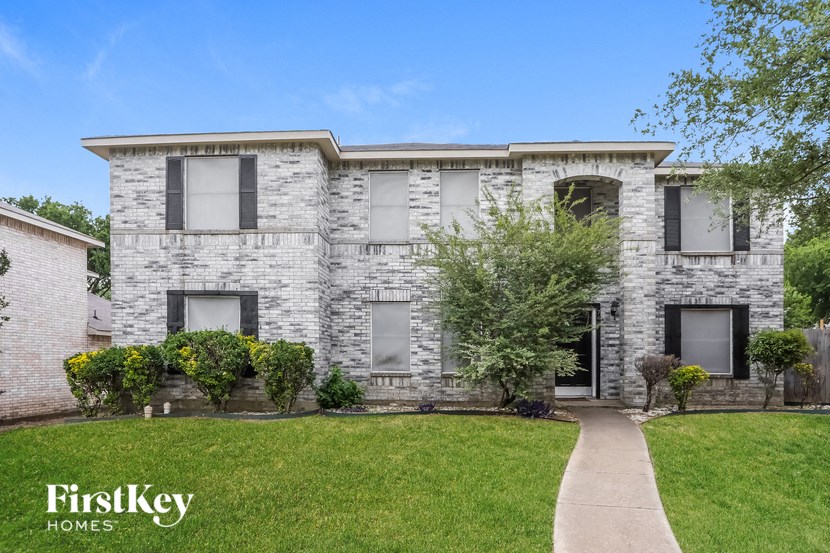 a white brick house with black windows and a sidewalk
