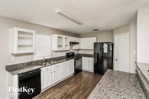 a kitchen with white cabinets and a black refrigerator