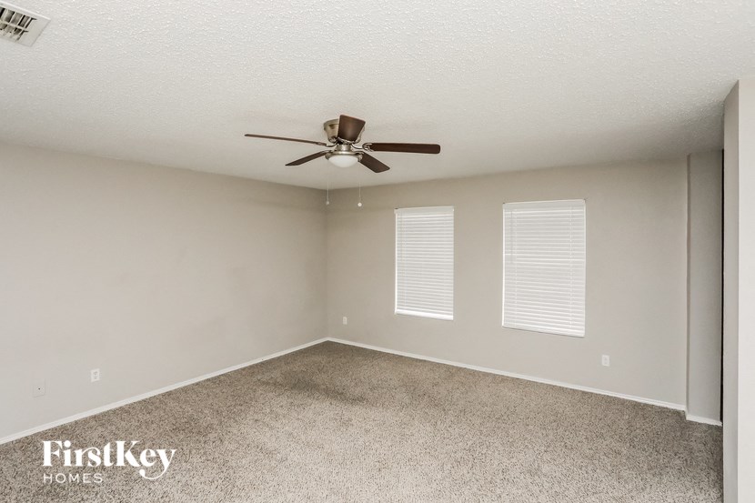 an empty room with a ceiling fan and two windows