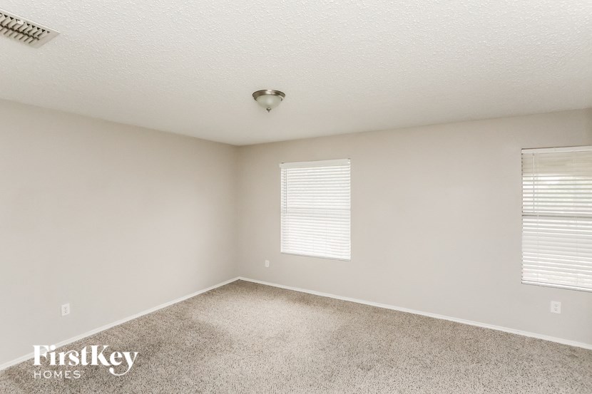 a bedroom with a carpeted floor and two windows