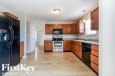 A kitchen with wooden cabinets and a black fridge.