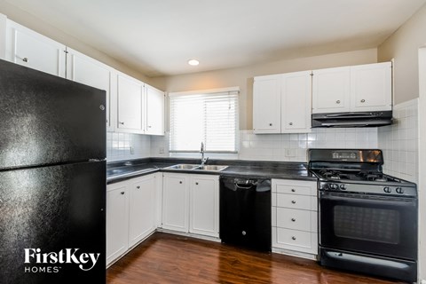a white kitchen with black appliances and white cabinets