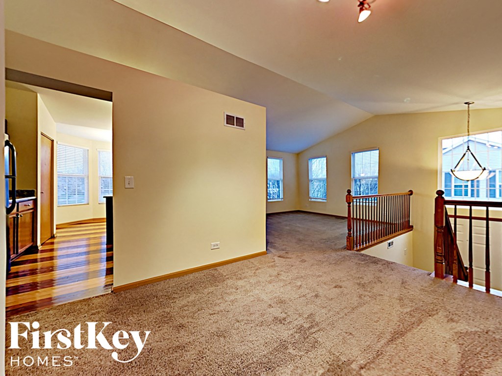 A spacious living room with a carpeted floor and a balcony with a railing.