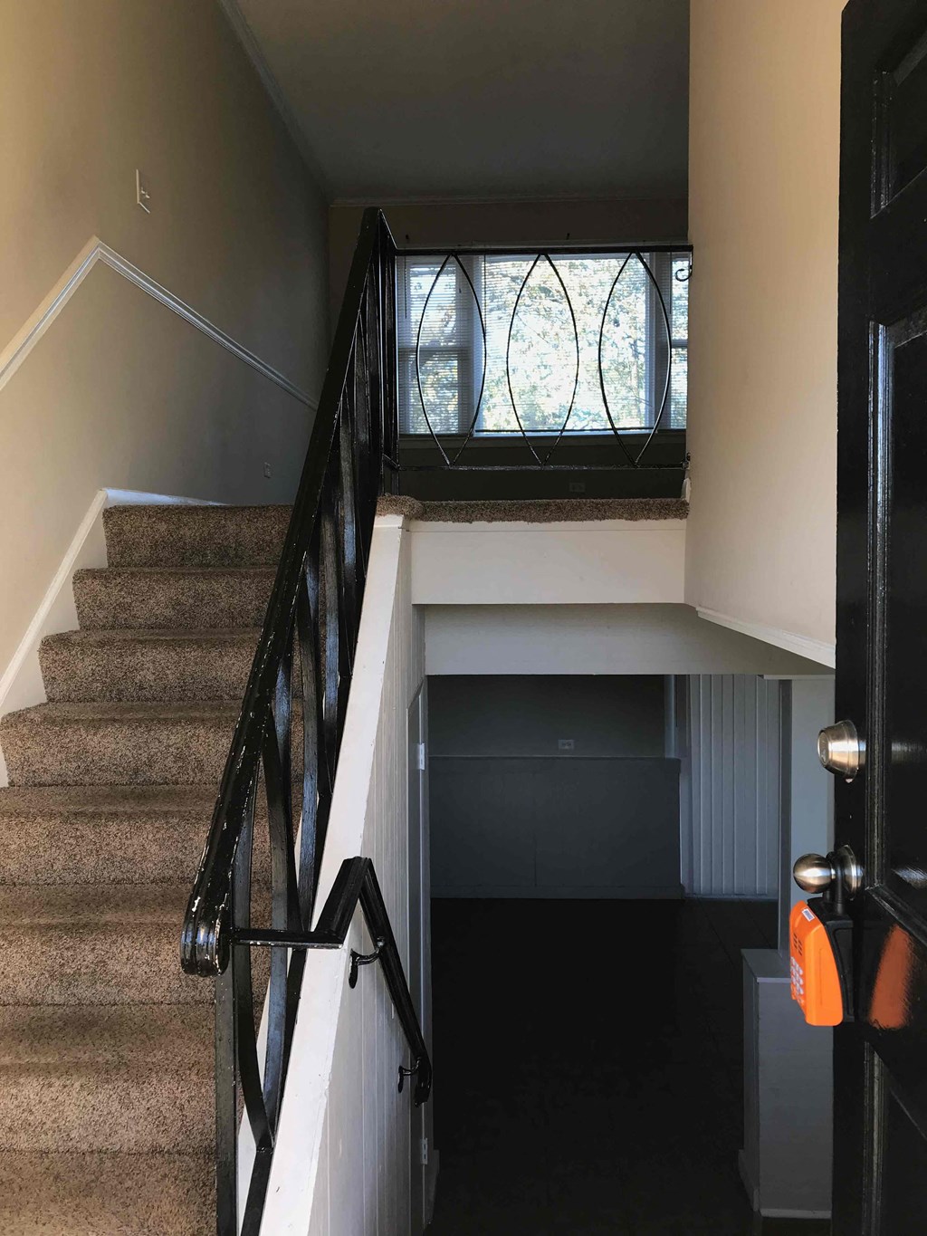 A staircase with a black railing and a brown carpet.