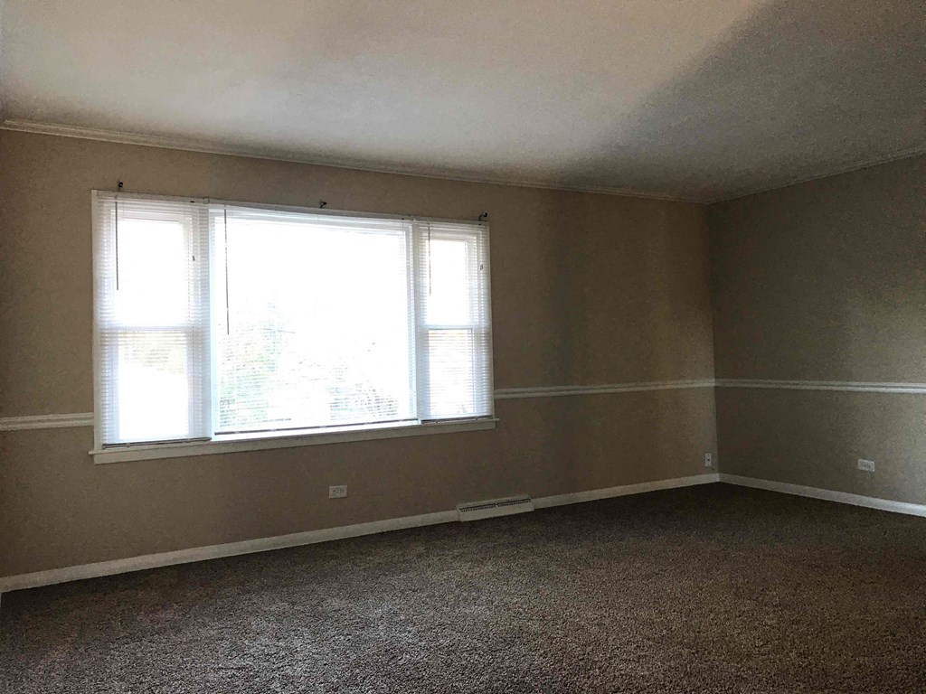 A room with a window and carpeted floor.