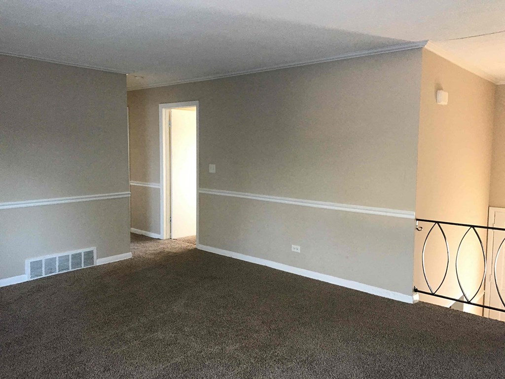 A room with a carpeted floor and a doorway leading to another room.