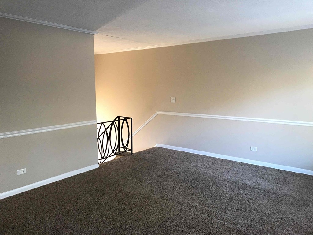 A room with a carpeted floor and a wall-mounted light fixture.