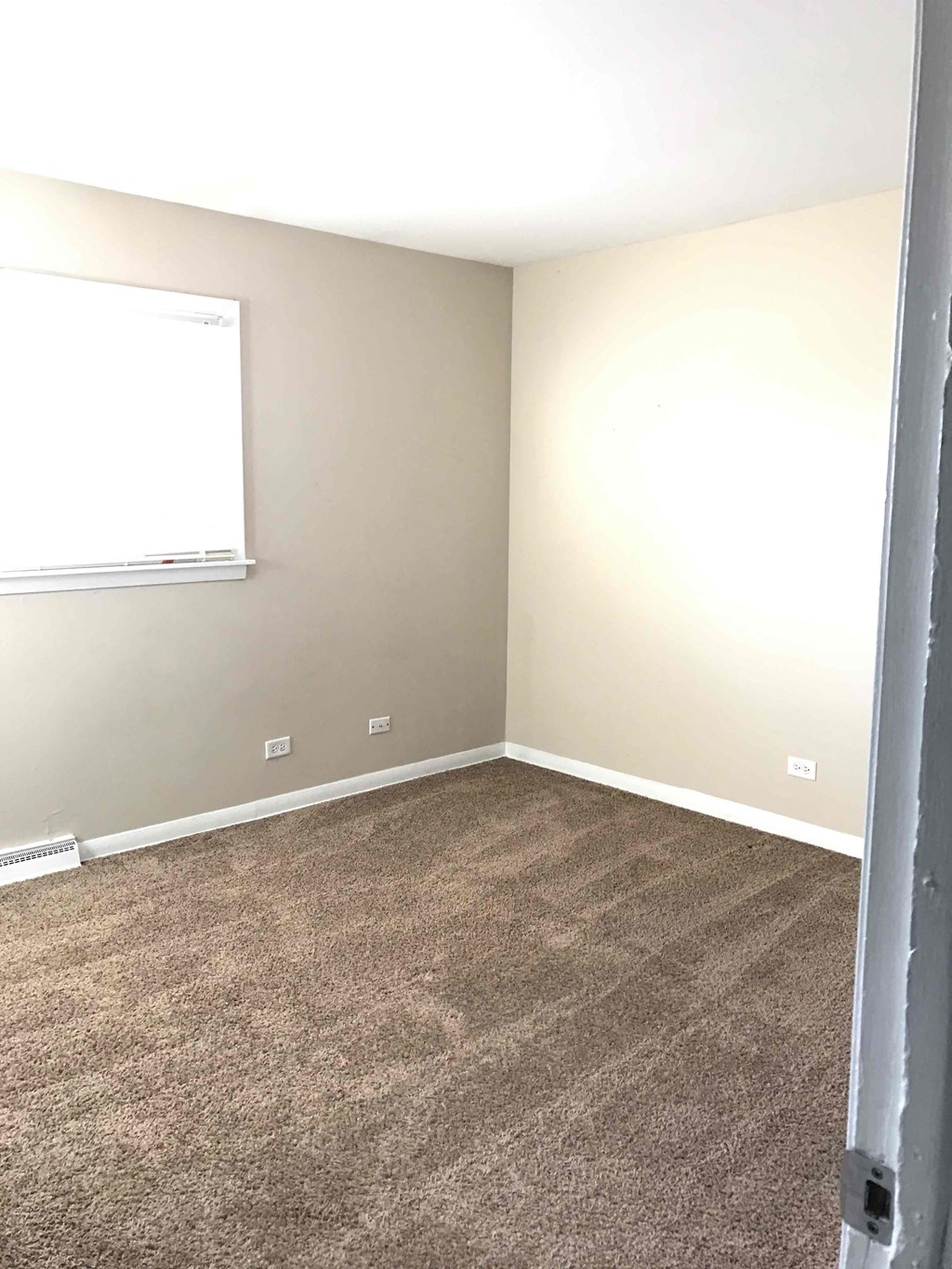 A room with a carpeted floor and a window.