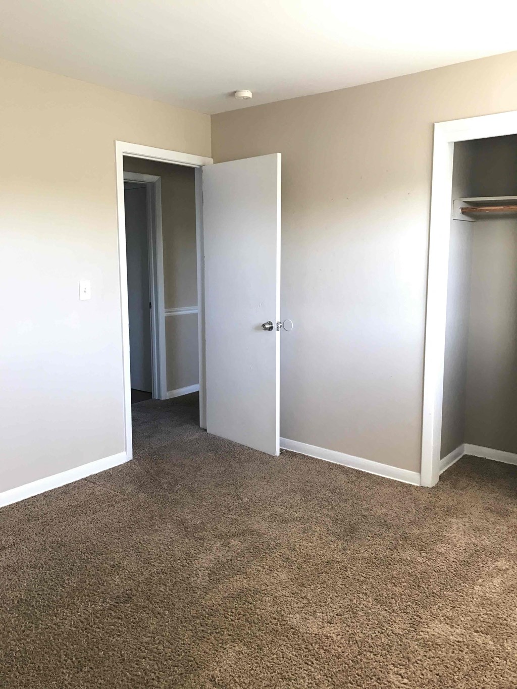 A room with a carpeted floor and a white door.