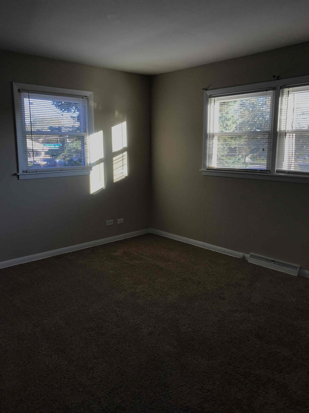 A room with two windows and carpeted floor.