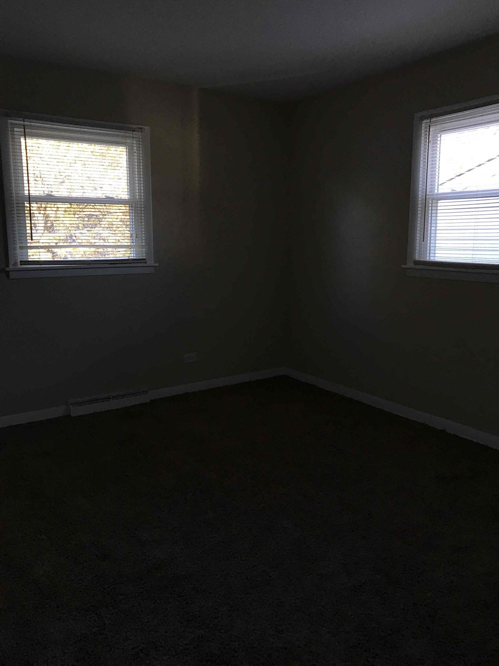 A room with two windows and carpeted floor.
