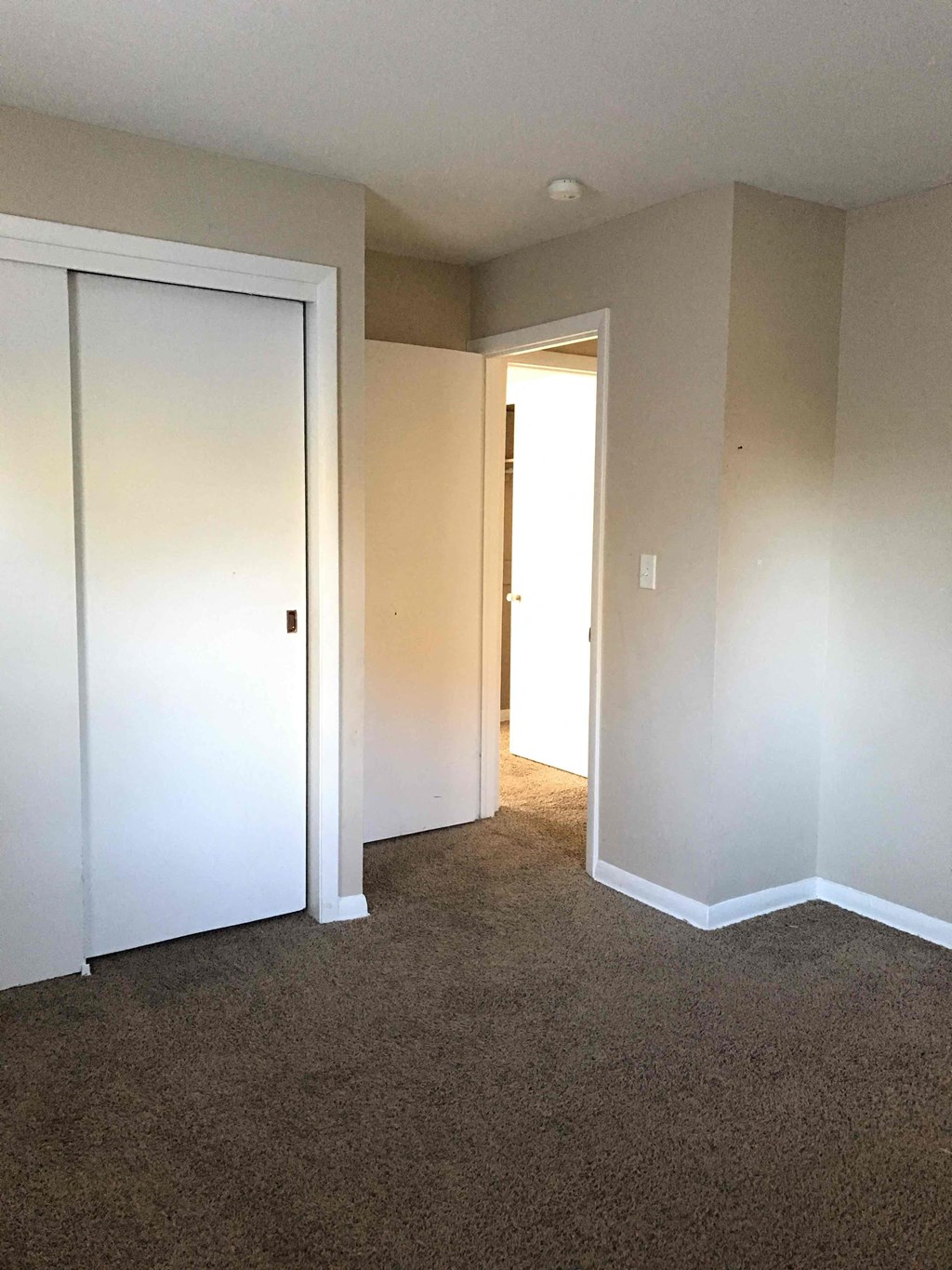 A white door is closed in a room with carpeted floor.