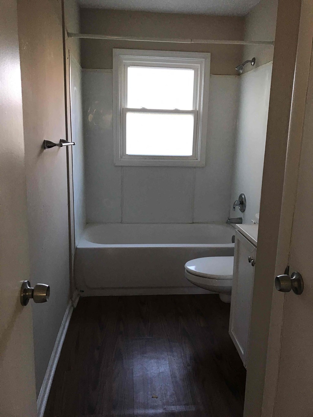 A small bathroom with a toilet, tub, and window.