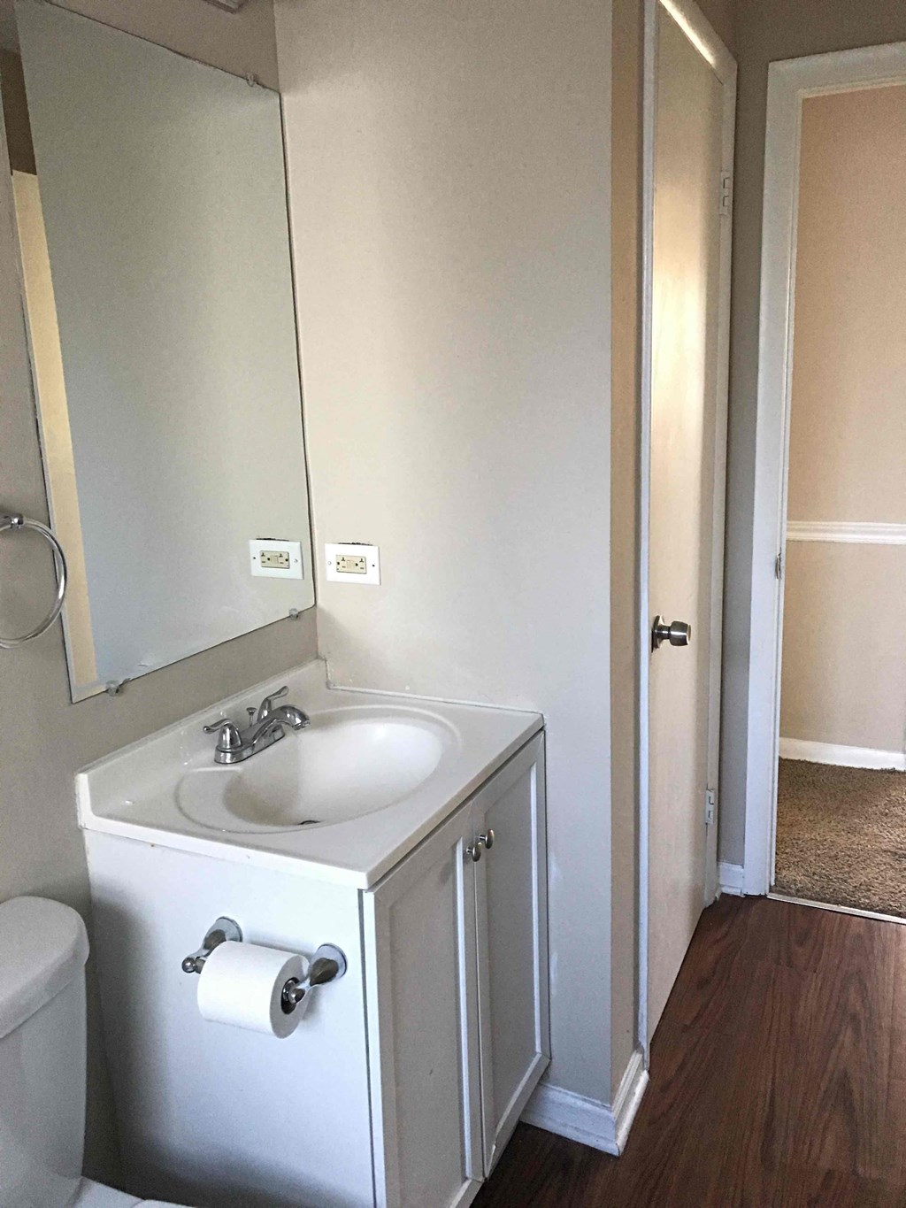 A white bathroom with a toilet, sink, and mirror.