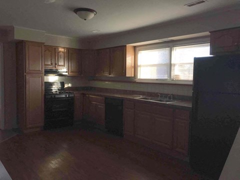 A kitchen with wooden cabinets and a black refrigerator.