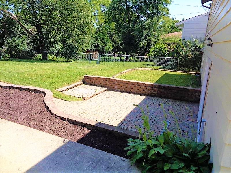 A backyard with a brick wall and a fence.