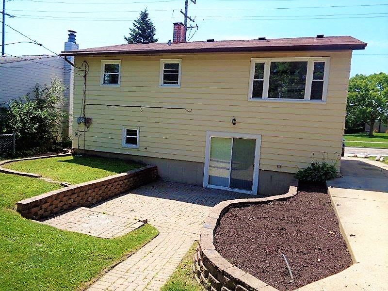 A yellow house with a red roof and a grey fence.