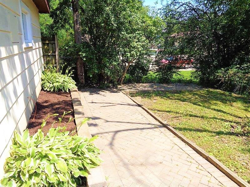 A white house with a brick pathway leading to a green lawn.