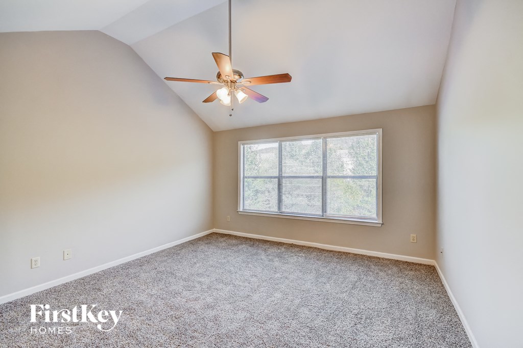 an empty bedroom with a ceiling fan and a window