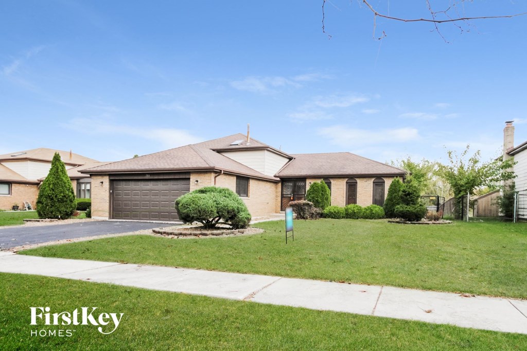 A house with a garage and a tree in front of it.