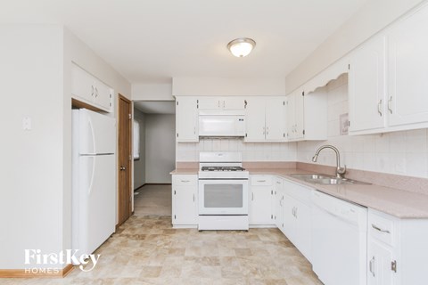 A kitchen with white appliances and cabinets.