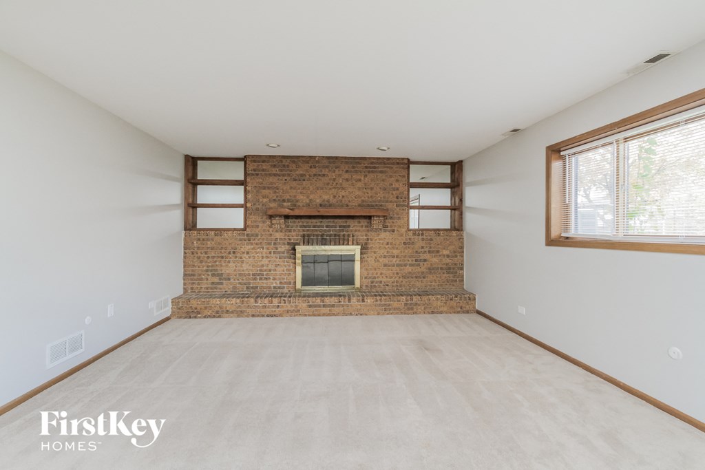 A room with a brick fireplace and a window.
