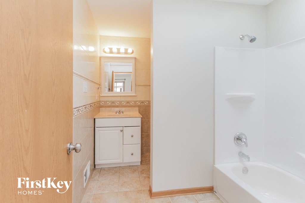 A bathroom with a tub, sink and mirror.
