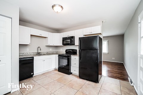 A kitchen with black appliances and white cabinets.