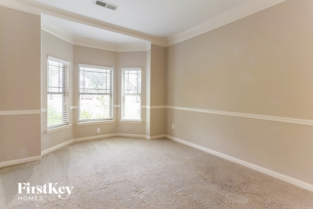 a empty living room with three windows and a carpeted floor